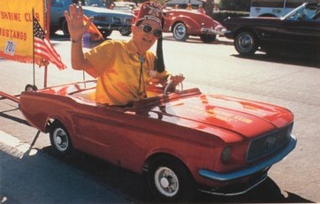 Featured is a postcard image showing an oversized Shriner in an undersized Mustang ... obviously it's a parade.  The photo is by the marvelous (and Internationally renown) street photographer Mike Marcus.  The original unused postcard is for sale in The unltd.com Store.